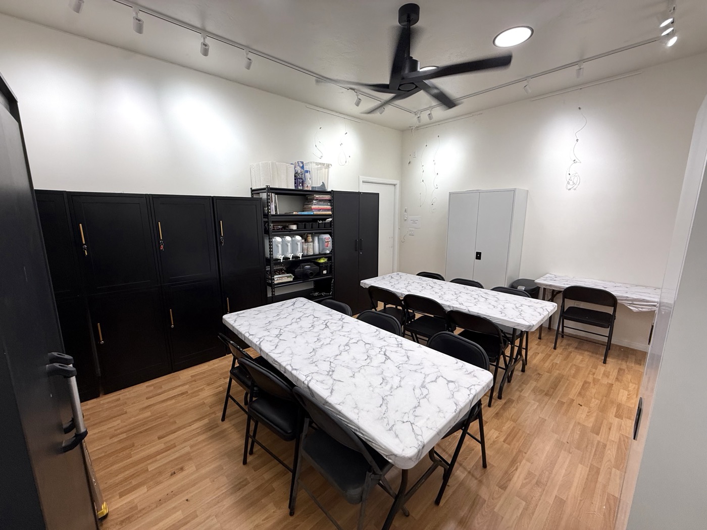 Studio 3B at ArtHatch: two long work tables with chairs, track lighting and storage cabinets